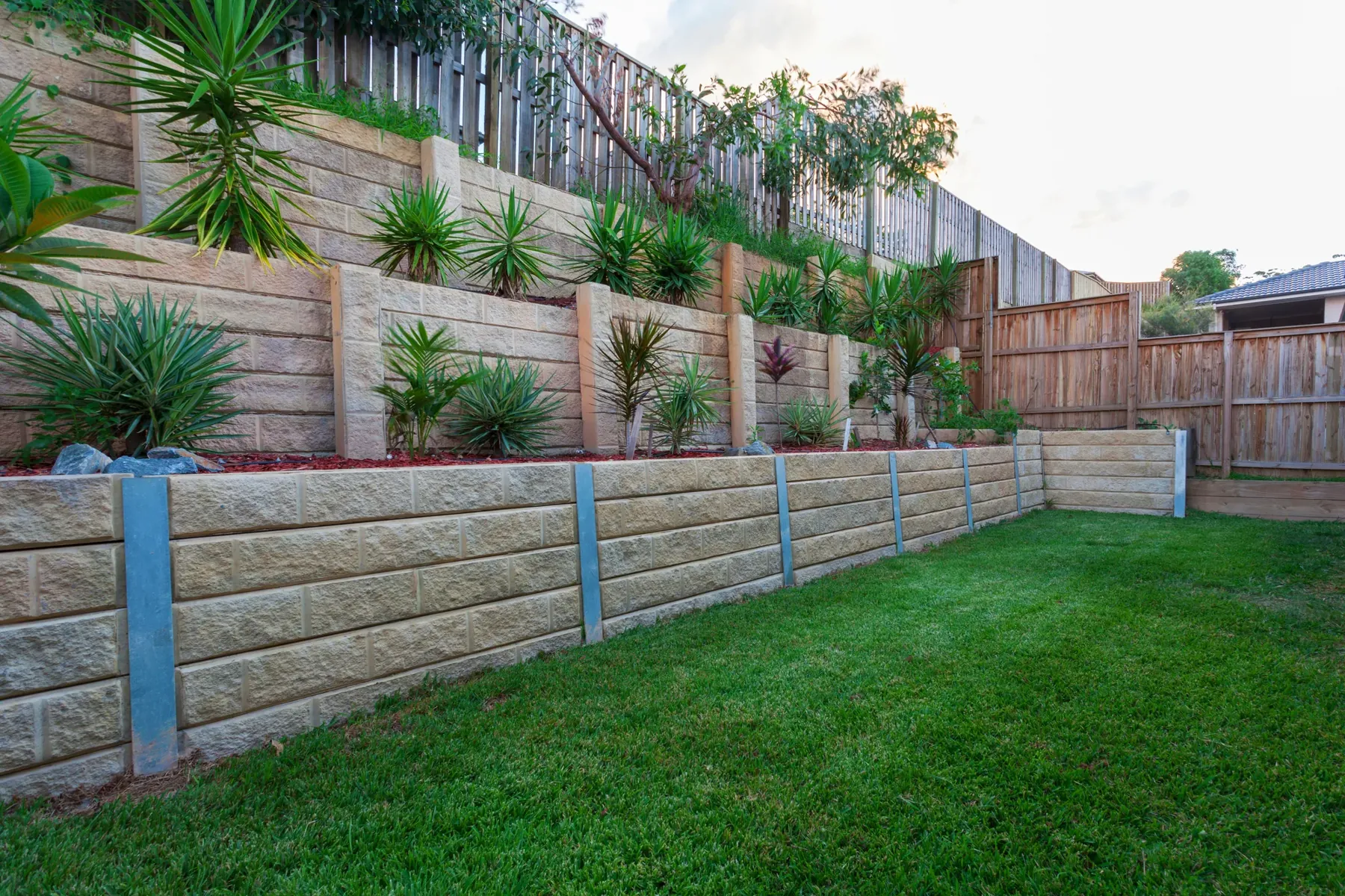 Multi-level concrete sleeper retaining walls terracing a backyard slope