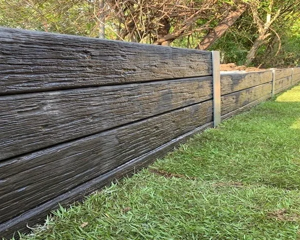 Concrete sleeper retaining wall with a timber-look finish along a lawn