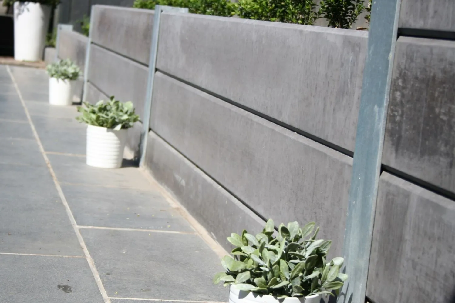 Smooth grey concrete sleeper wall beside a paved courtyard