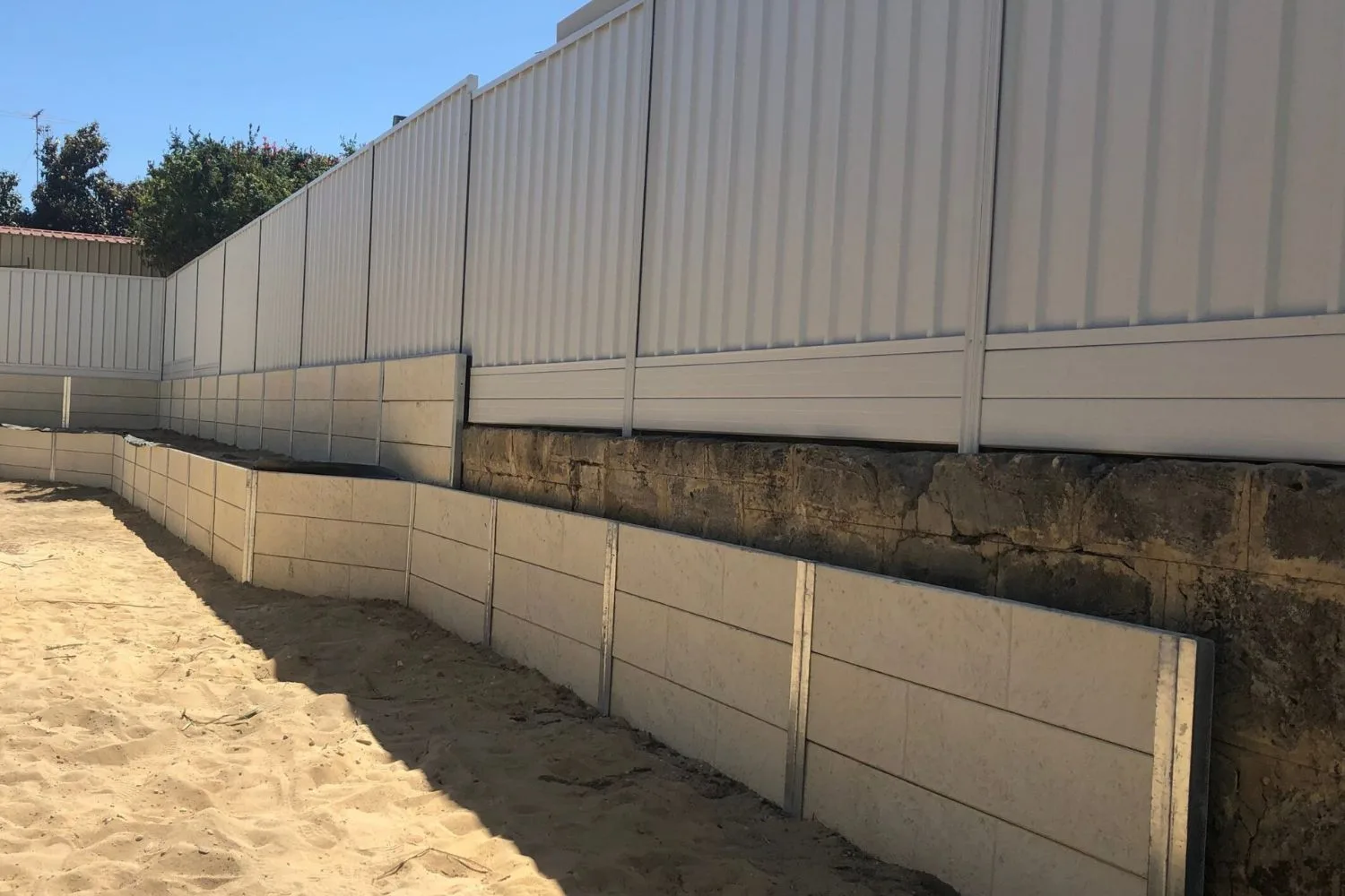 Concrete sleeper retaining wall built along a sandy boundary