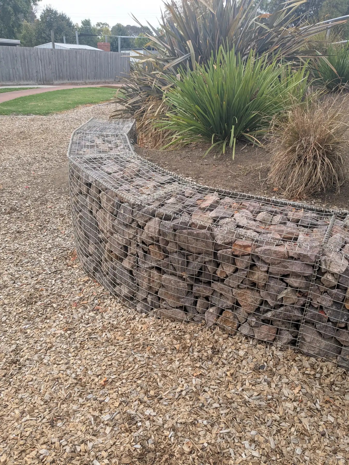 Close view of a curved gabion wall with native grasses planted above