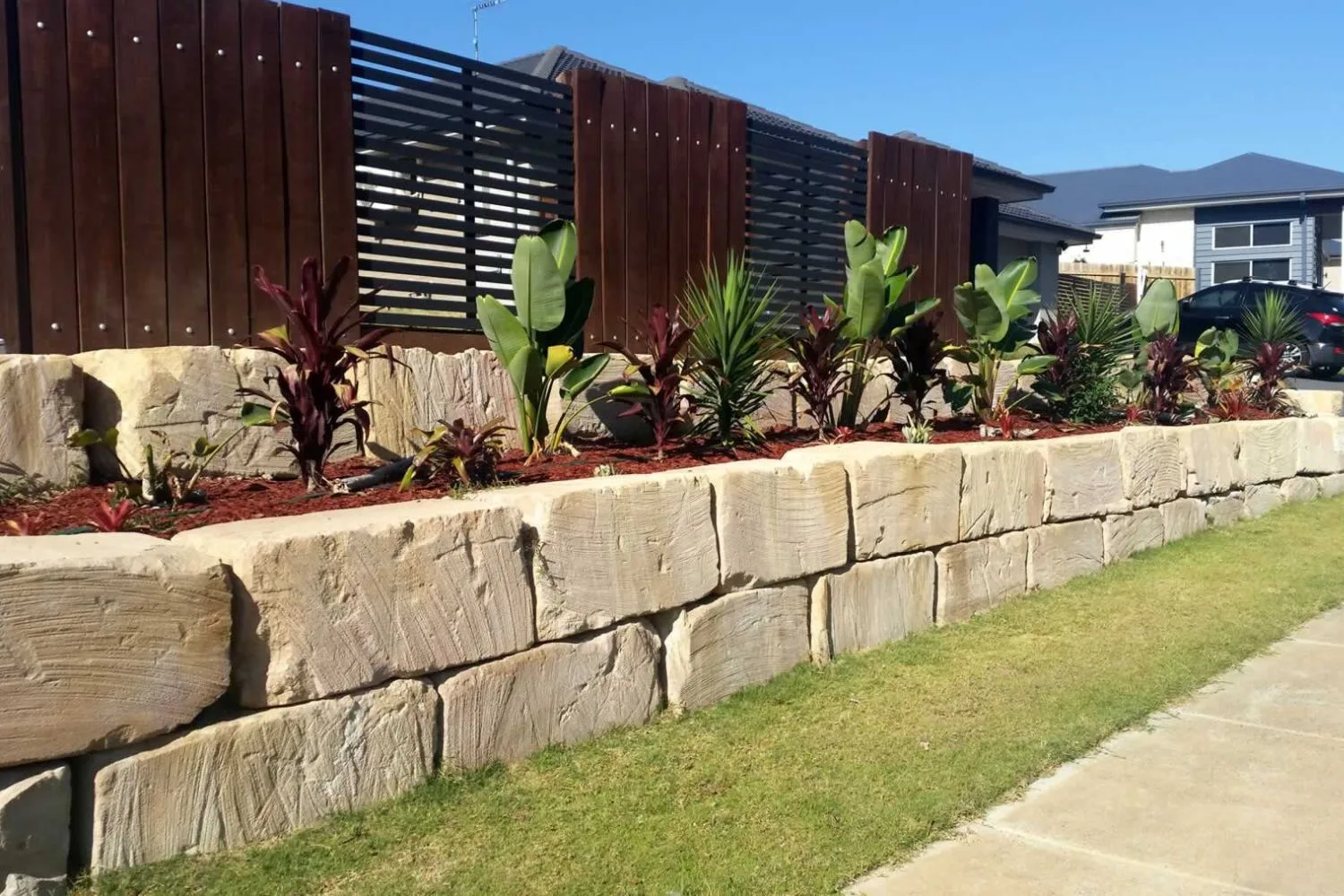 Sandstone block retaining wall along a garden path and fence