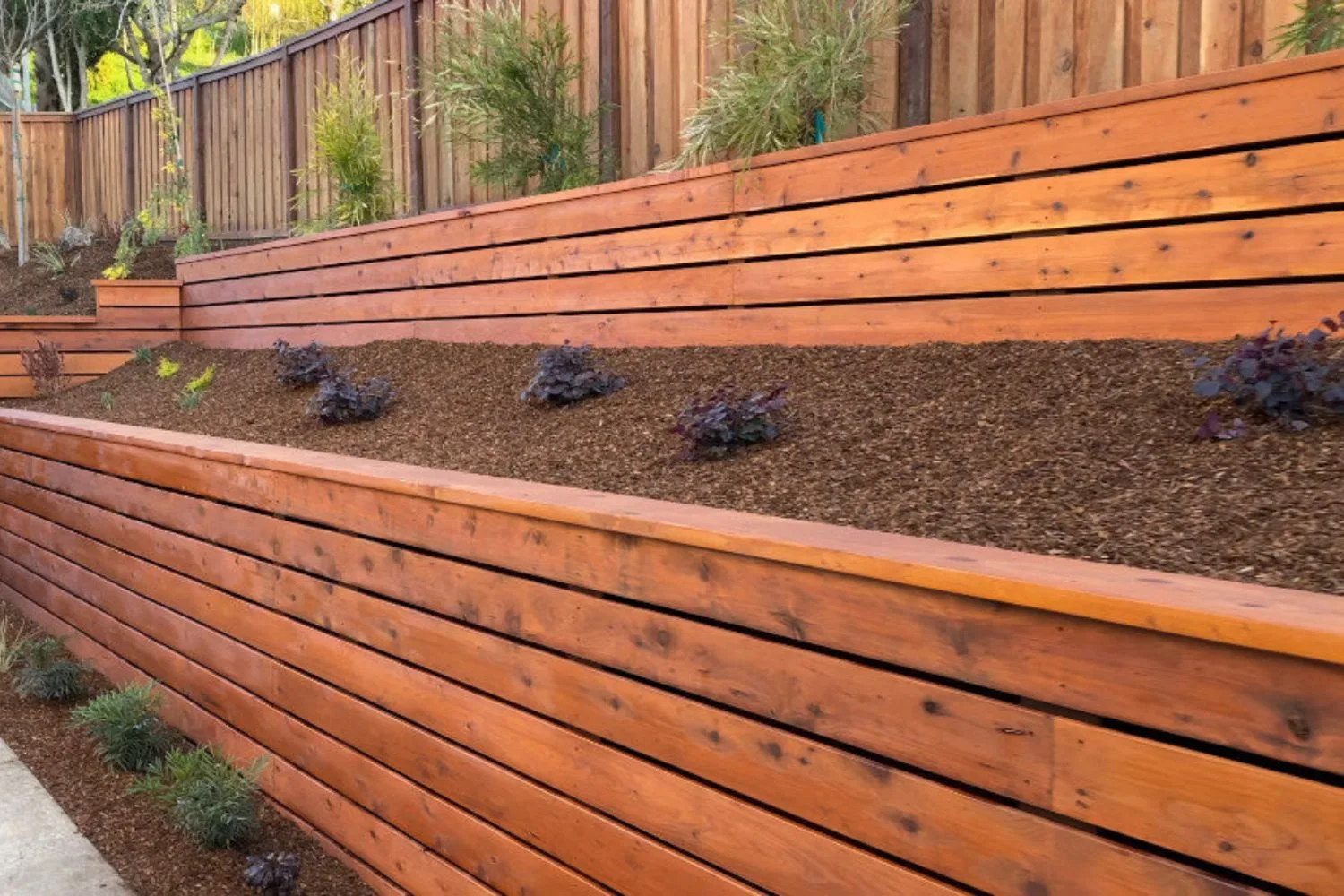 Long timber sleeper retaining wall along a fence line