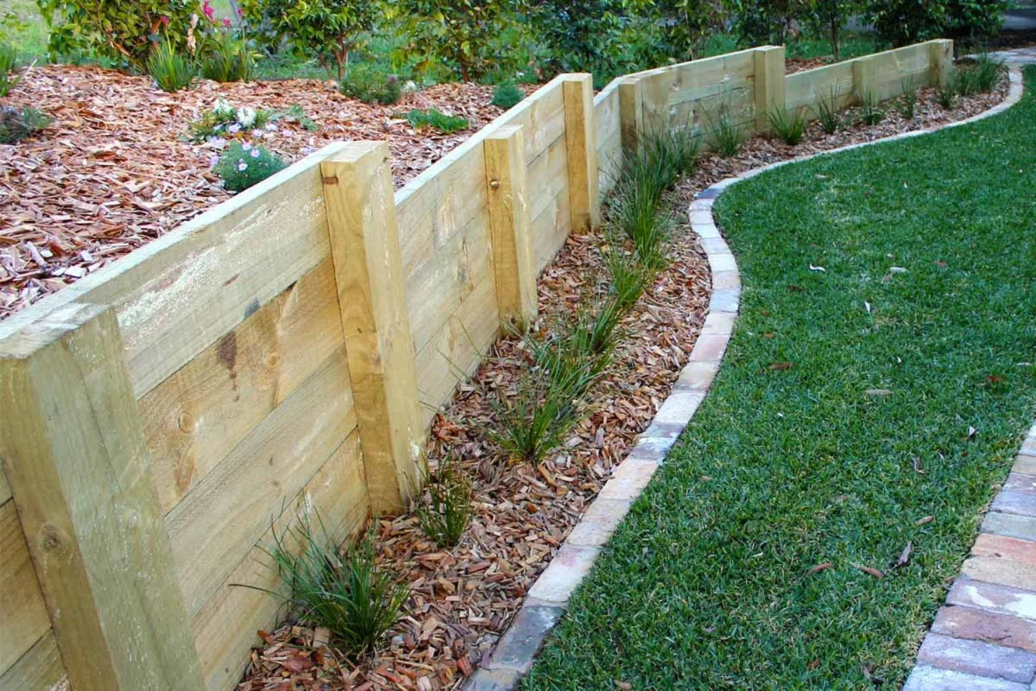 Stepped timber sleeper retaining wall beside a curved lawn